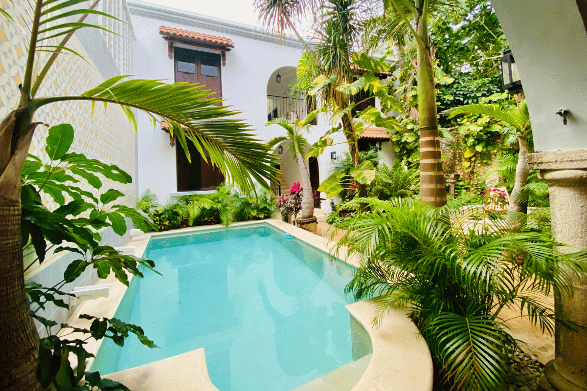 Lush colonial courtyard pool surrounded by palms and patterned tile at a long term rental in Mérida Mexico