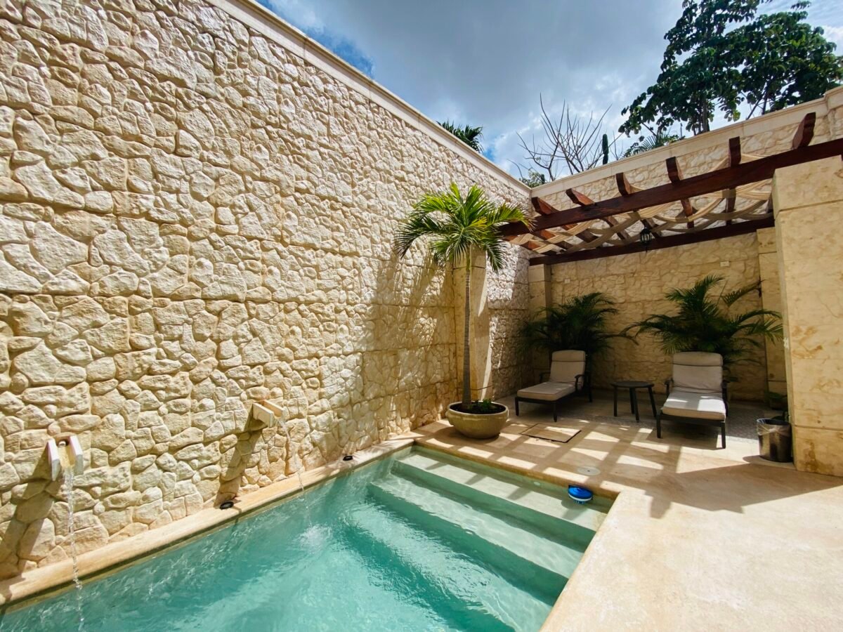 Modern plunge pool with limestone wall, water features, and shaded pergola at a renovated Mérida rental