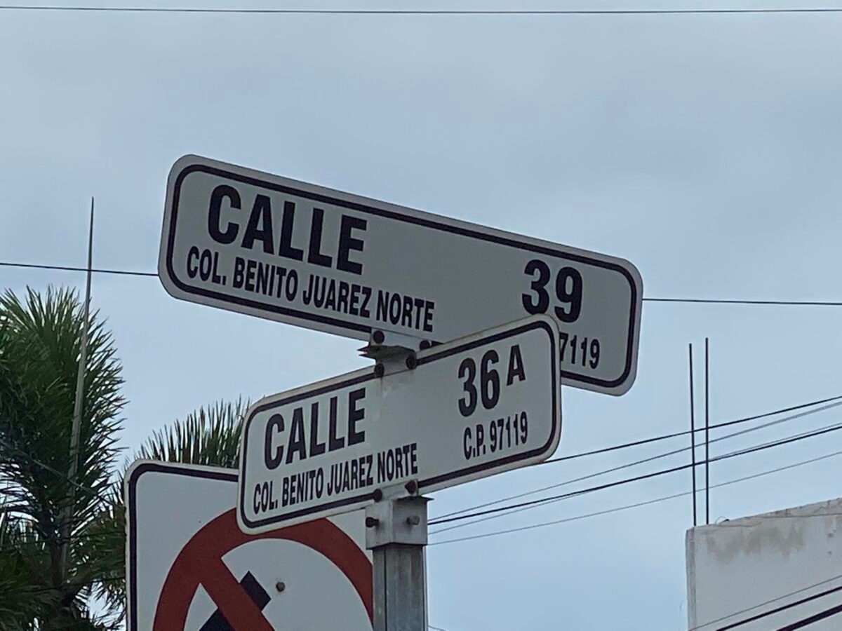 Black and white street sign on a corner in a neighborhood in Merida Mexico