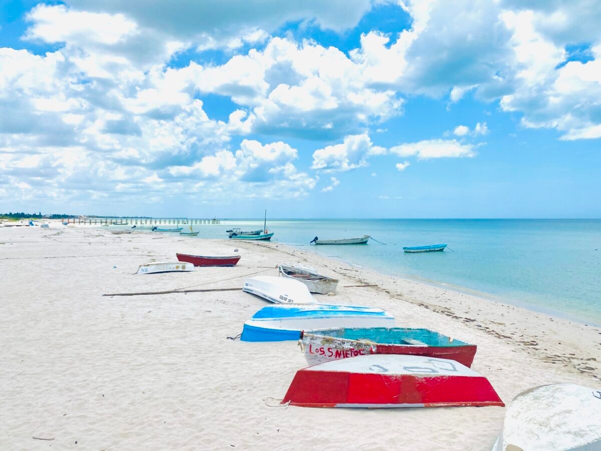 Colorful fishing boats lined up on a calm white sand beach along the Gulf Coast near Mérida, Yucatán