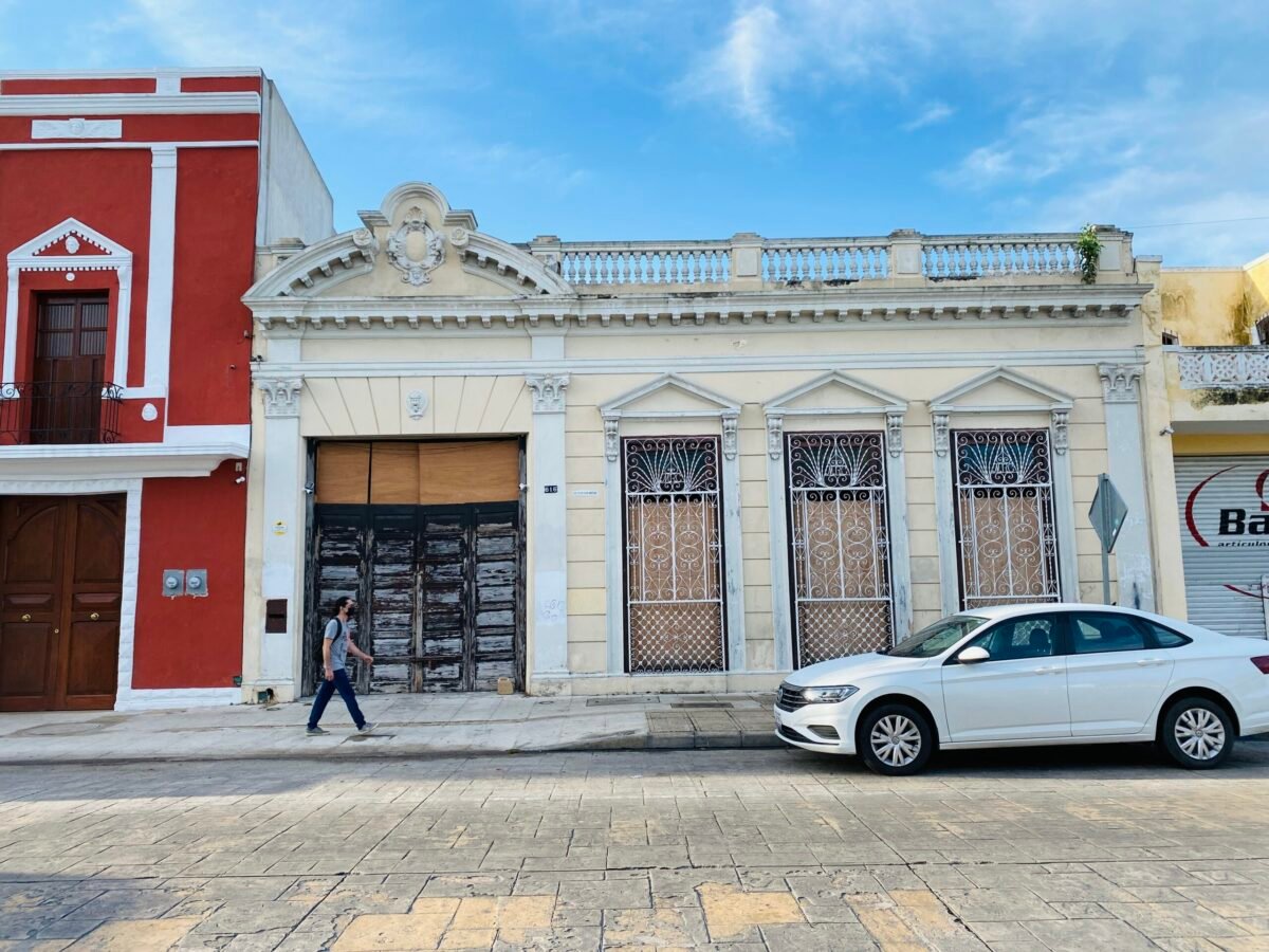 Person walking in front of while colonial house in merida mexico centro