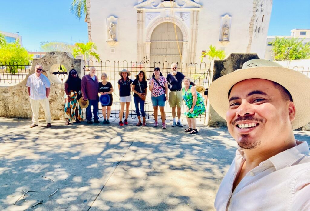 Angel Rodriguez leading a Life in Mérida group scouting trip in front of a colonial church in Mérida, Yucatán