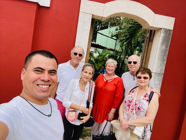 Angel Rodriguez and Amy Jones of LIfe in Merida with scouting trip clients underneath a red arch